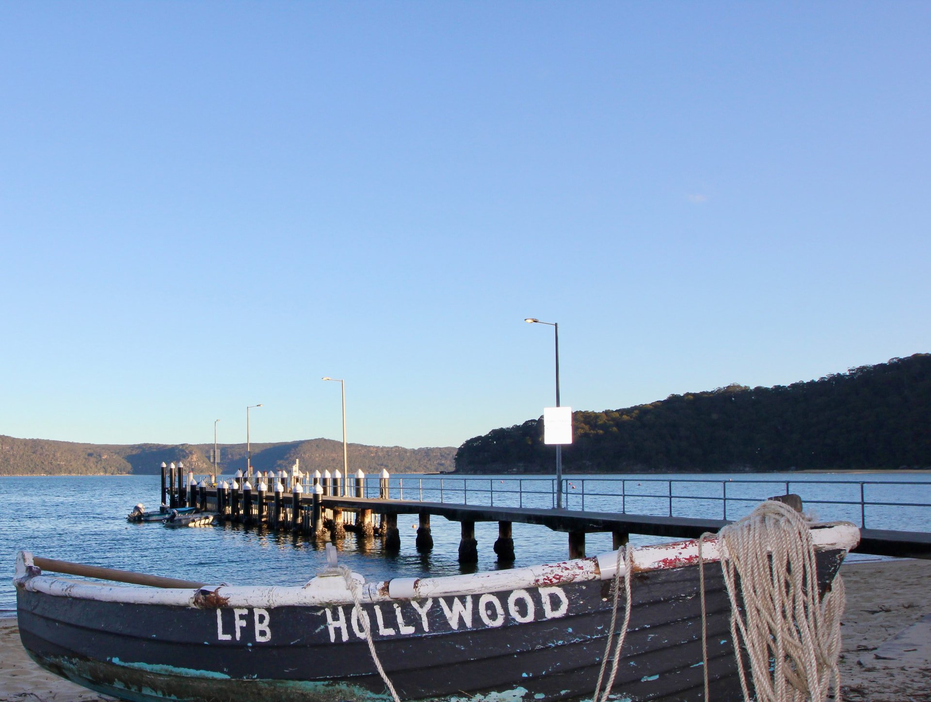 Patonga wharf reaching into Broken Bay with an old timber surfboat on the sand