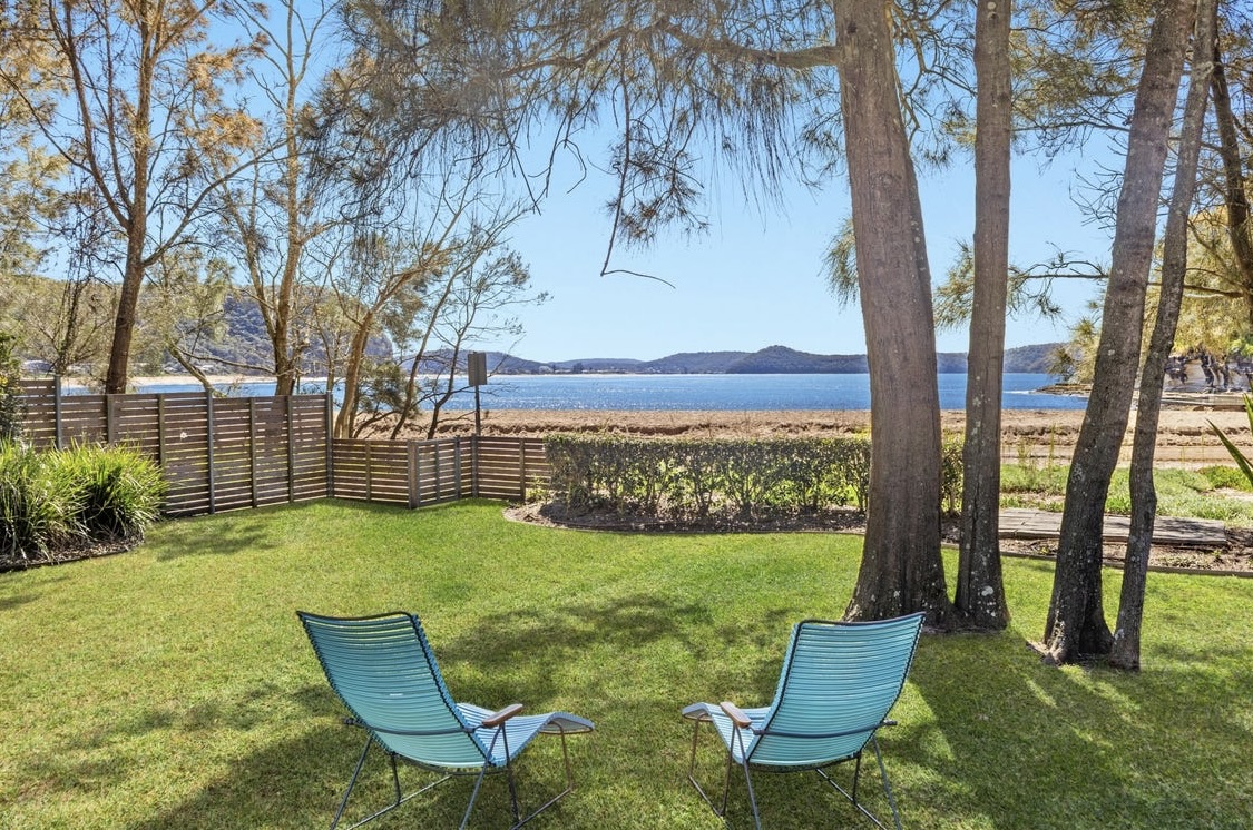Two aqua loungers on the back lawn under casuarinas, looking across to Pearl Beach