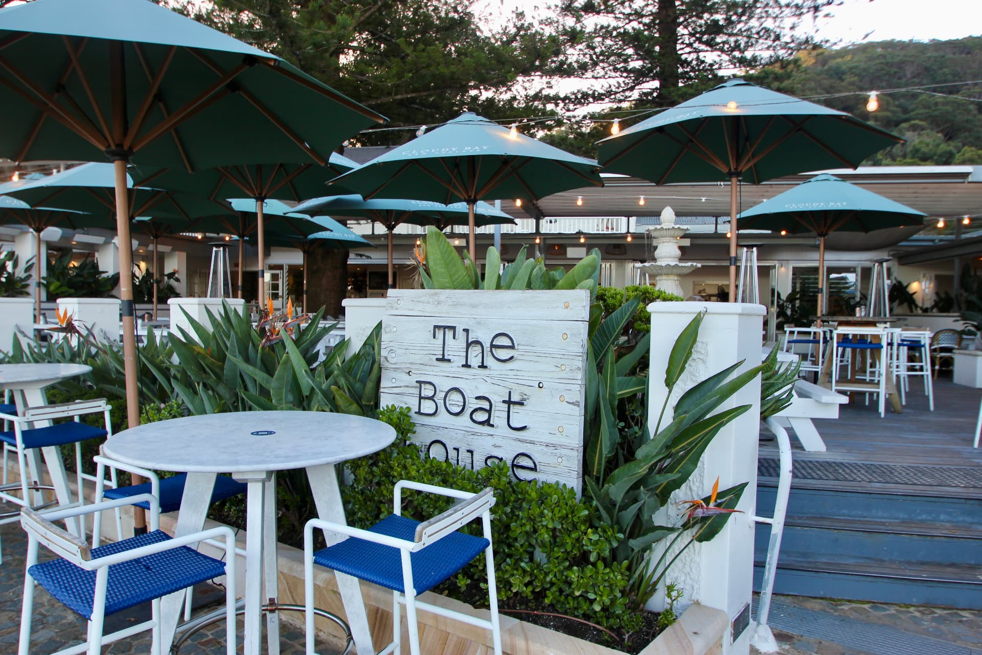 The Boathouse Hotel sign and umbrella-shaded tables at Patonga