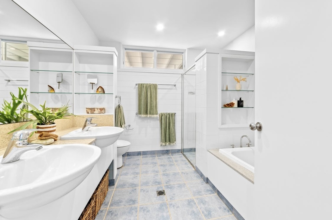 Downstairs bathroom with twin basins, walk-in shower and soft blue tiled floor