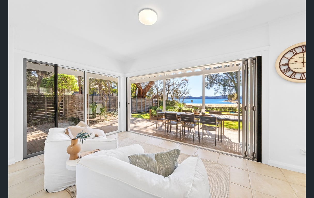 Downstairs living room looking out through bifold doors to the deck, garden and beach