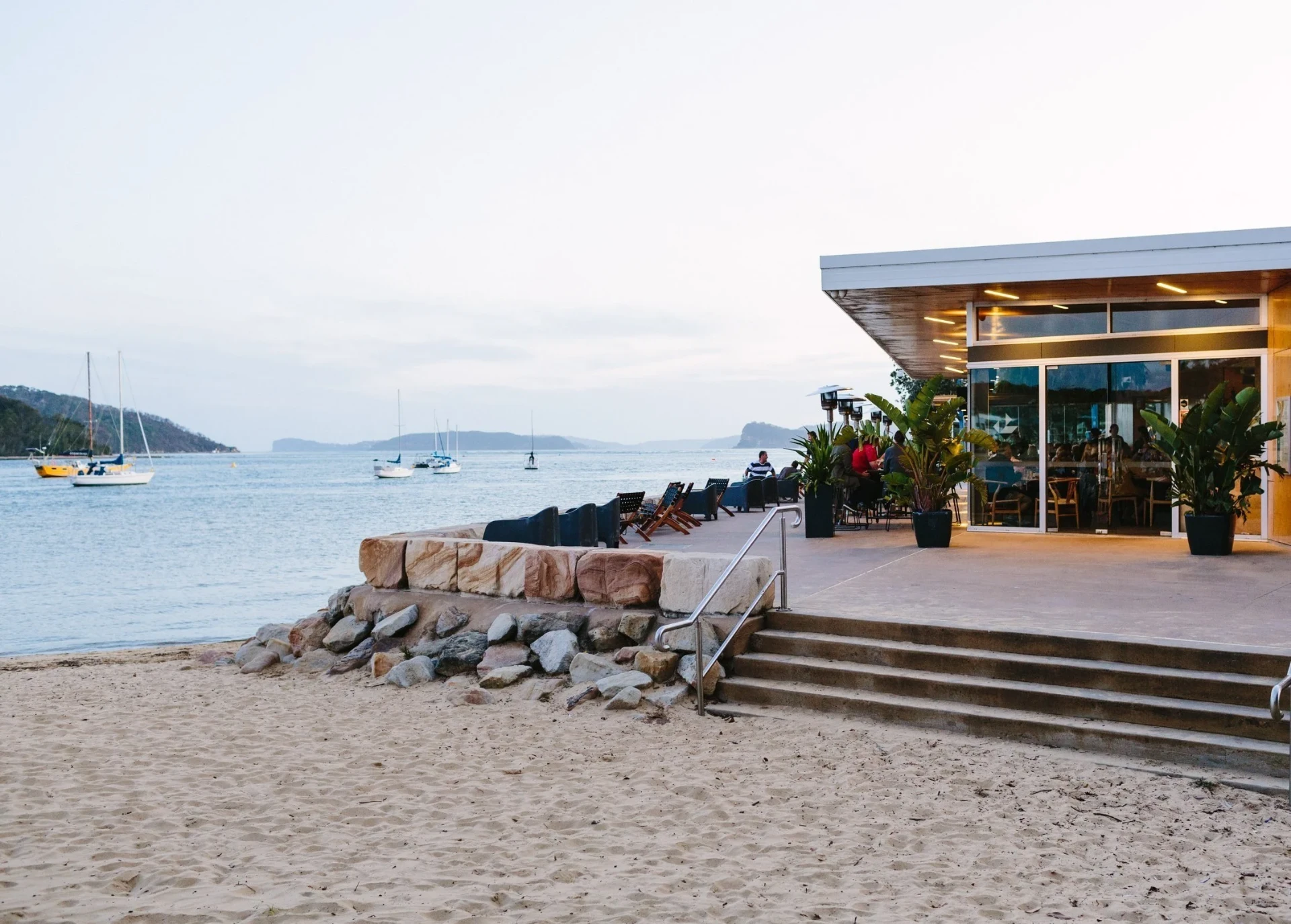 The Box restaurant on the waterfront at Ettalong, with boats moored on the water and diners seated on the outdoor terrace