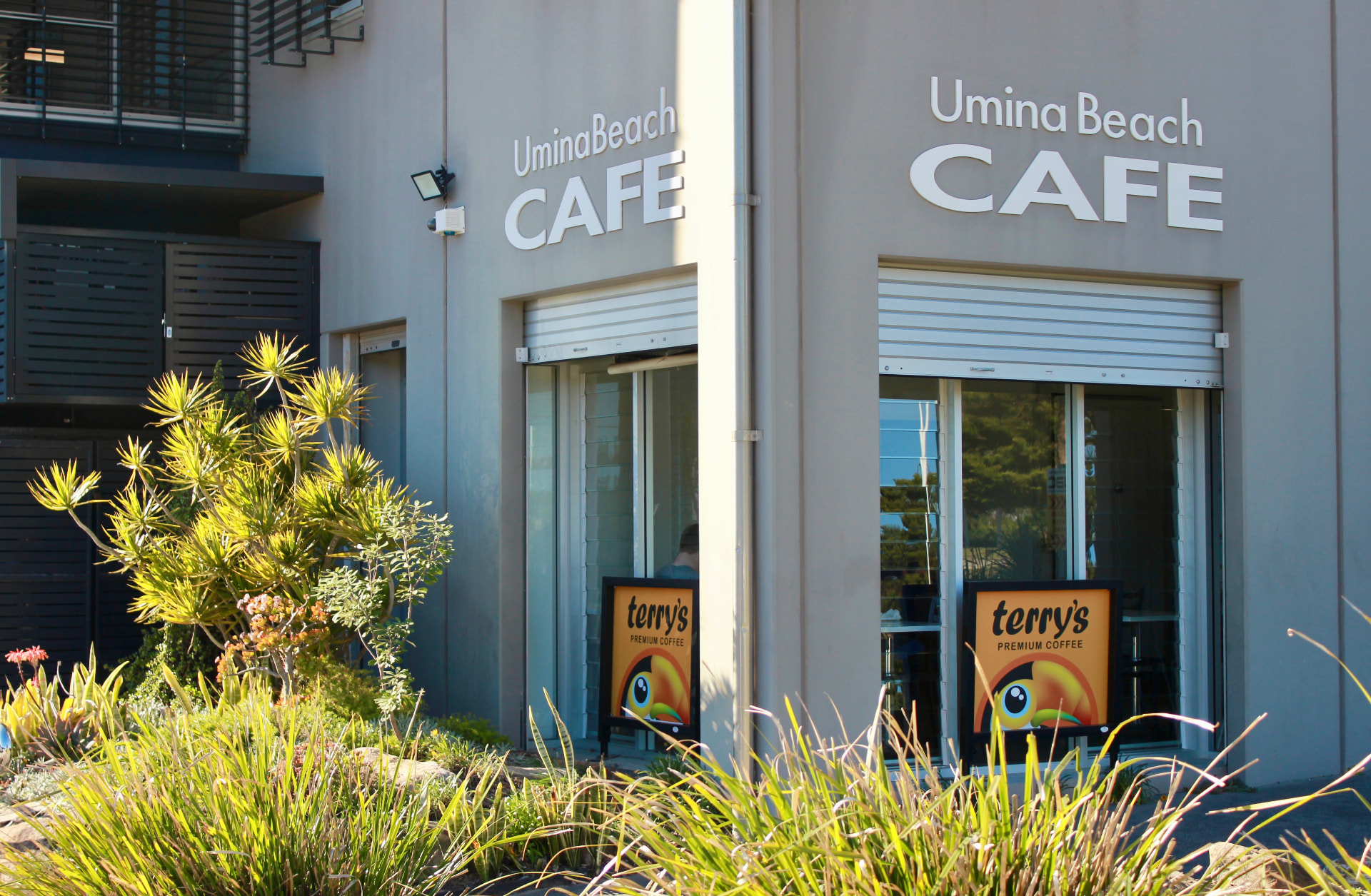 The Umina Beach Cafe frontage with coffee signs and native planting