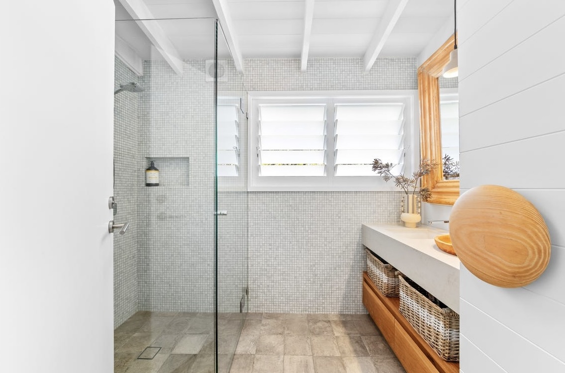 Upstairs bathroom with mosaic-tiled walk-in shower, timber vanity and louvre windows