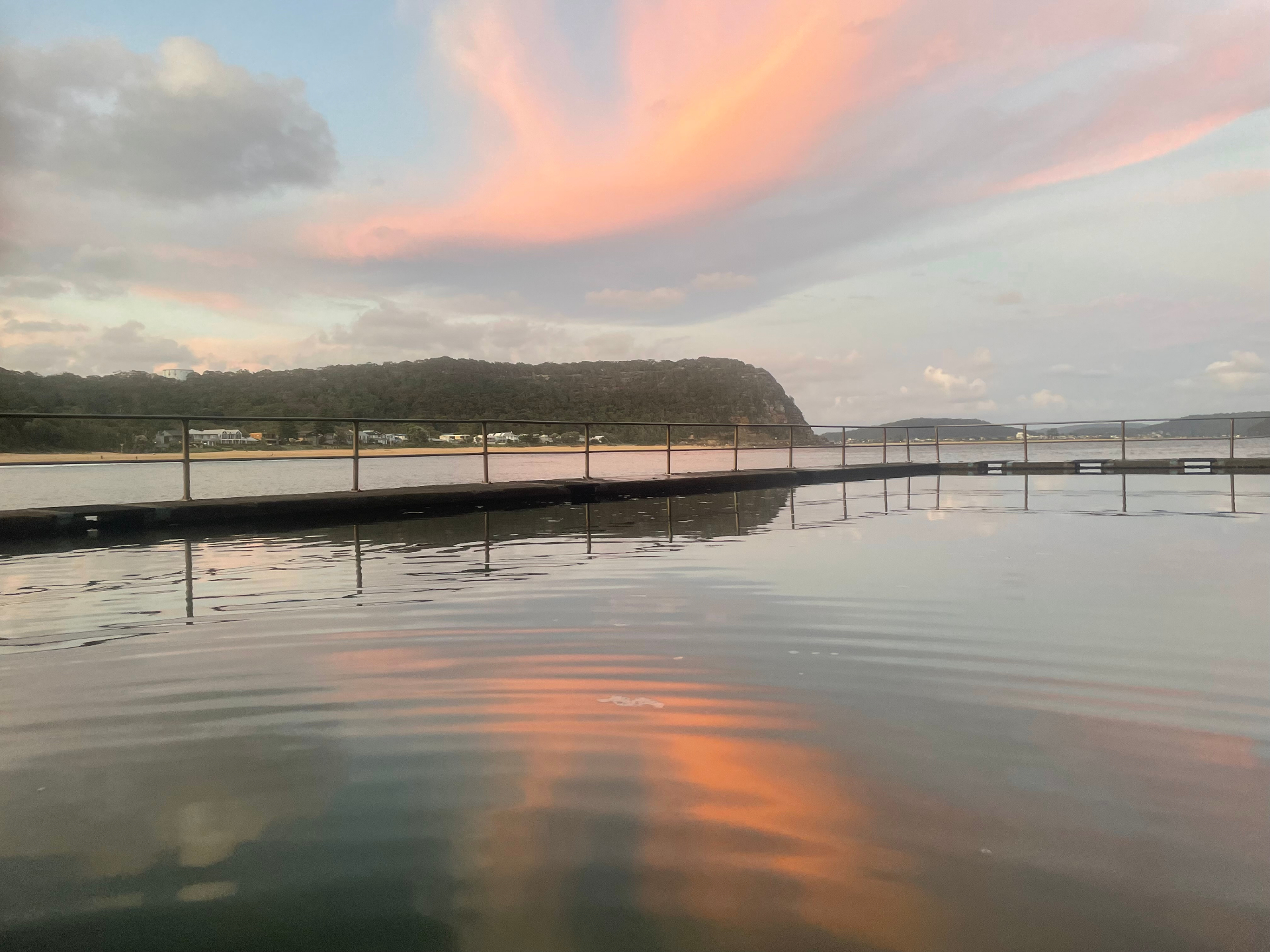Evening view of the Pearl Beach rock pool with sunset colours reflected in the water