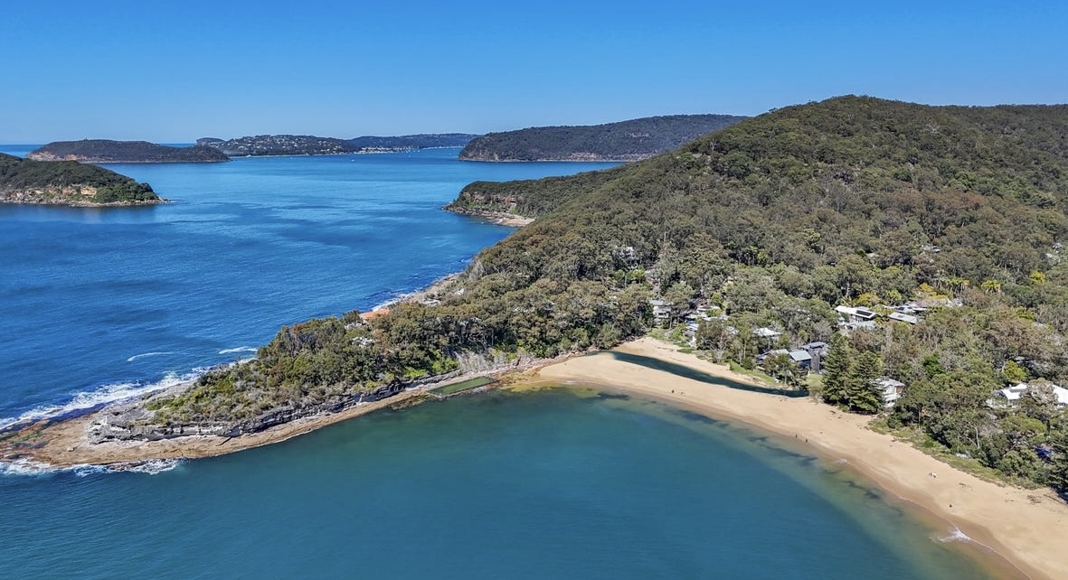 Aerial view of the Pearl Beach crescent on the NSW Central Coast — sand, headland and bushland